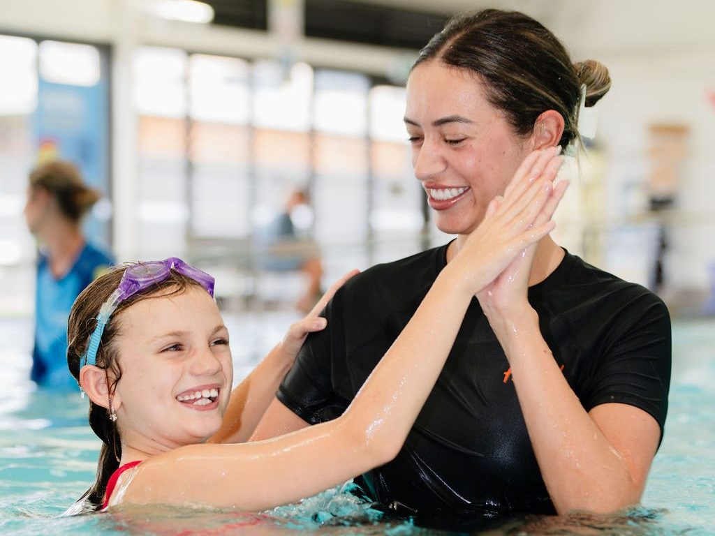 Swim instructor celebrating with a young participant during an inclusive lesson
