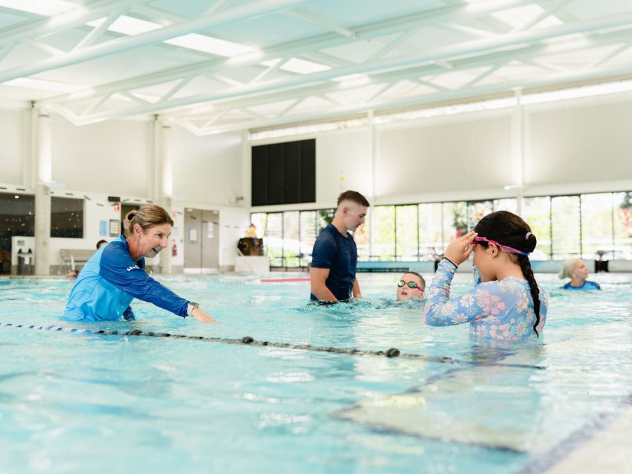 Instructor supporting a group of swimmers during a Thryv Swim session